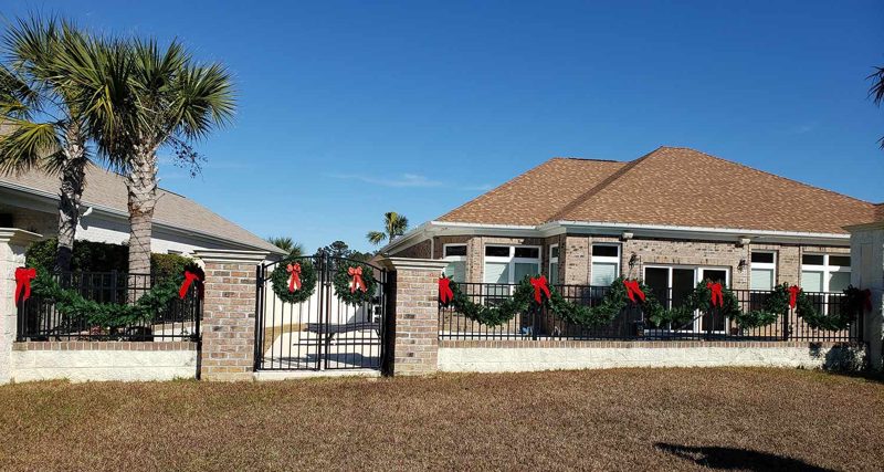 Brick home with red-bow garland on the fence and gate