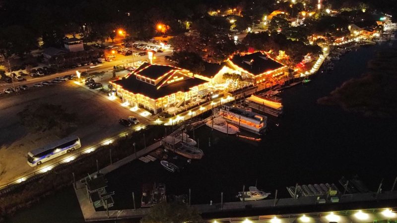 Aerial view of a waterfront restaurant with lit rooflines and docks