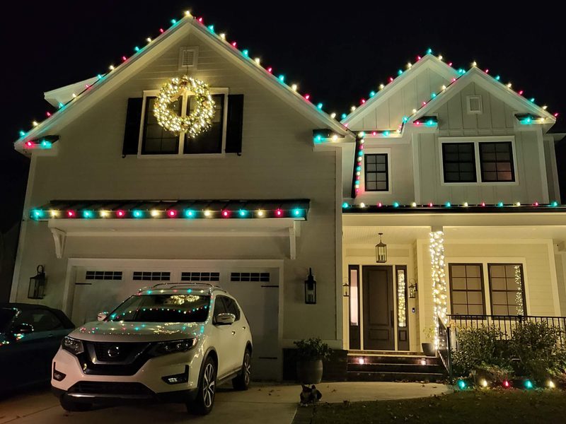 Two-story home in Myrtle Beach with red, white and green roofline lights and a lit wreath