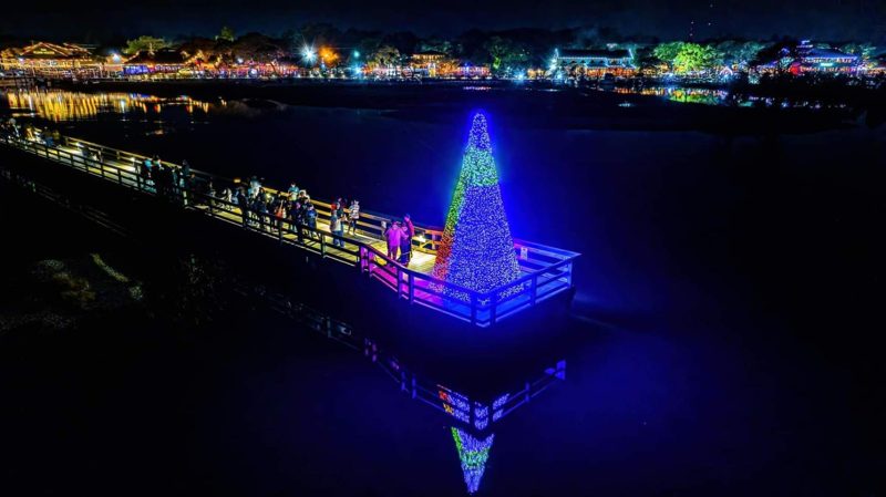 Aerial view of a lit Christmas tree at the end of a dock