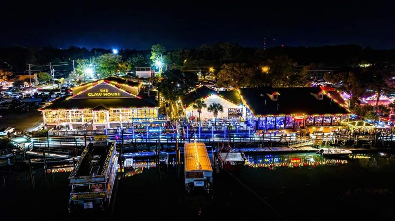 Aerial view of a waterfront boardwalk and restaurants lit for the holidays