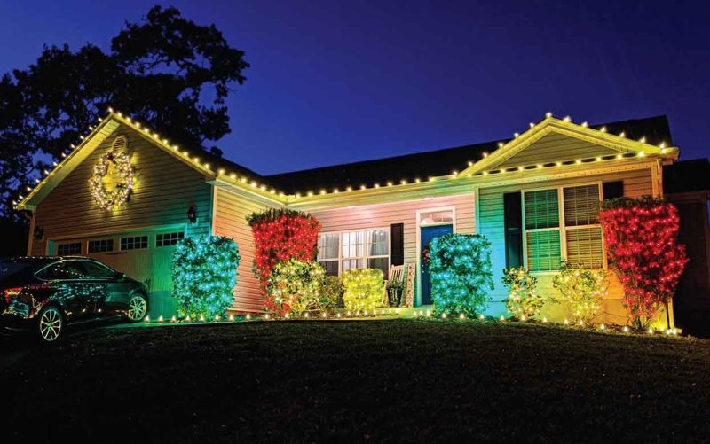 Ranch home in Longs, SC with warm white roofline lights and colorful lit shrubs